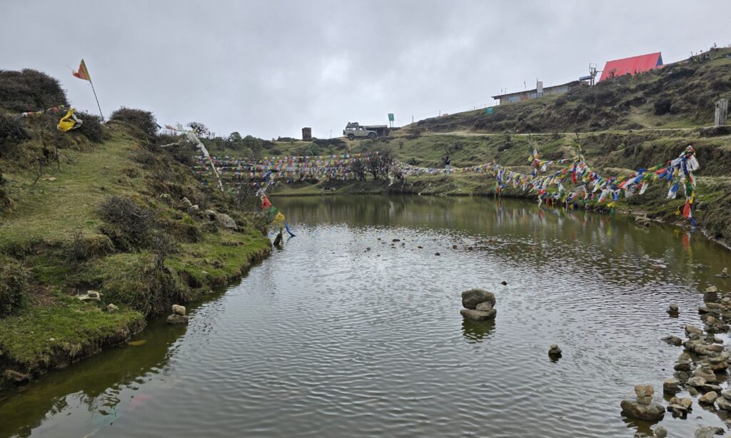 Kalipokhri, the sacred black lake surrounded by prayer flags and drifting clouds.