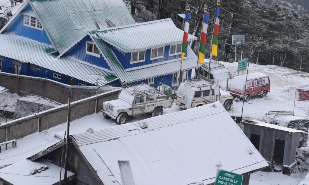Iconic vintage Land Rovers blanketed in fresh morning snow outside a mountain lodge in Sandakphu.